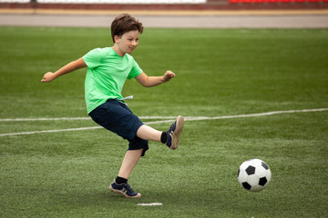 Obraz premium child run soccer (football) player. Boy with ball on green grass