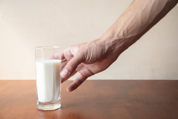 man's hand reaches for a glass of milk