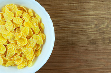 white bowl of corn flakes on wooden background