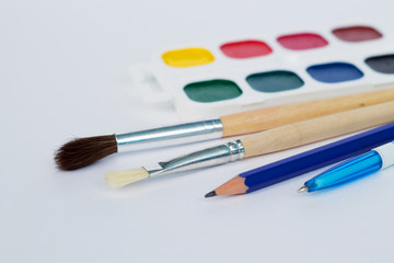 watercolor paints and brusheswith pen isolated on white