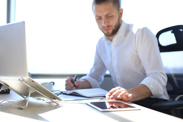 Fototapeta premium Close up hands of man touching tablet, multitasking on screen in an office.