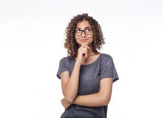 Portrait of a pensive Indian girl on a white isolated background. Young smiling woman in glasses is...