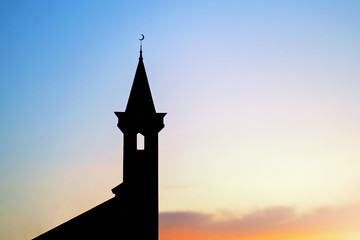 Fototapeta dark silhouette of a muslim mosque with a crescent on the spire at sunset obraz