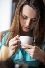 Girl in a cafe is drinking coffee. Portrait of a girl close-up.