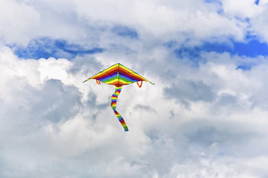 multi-colored kite flying in the sky on the background of clouds