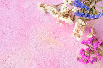 Bright colorful flowers with tiny petals and selective focus on pink plaster background. Spring backdrop with romantic flower board and copy space for text. Greeting card concept with spring flowers 