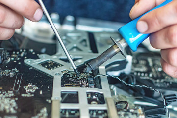 a man repairs a computer, solders a board, repairs electronics and modern technologies