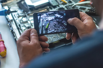 a man repairs a computer, solders a board, repairs electronics and modern technologies