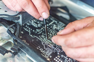 a man repairs a computer, solders a board, repairs electronics and modern technologies