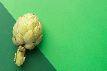 Ripe artichoke on duotone background of different shades of green color. Creative food poster for...