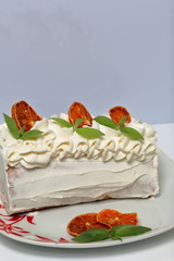 Sponge cream cake coated with cream and garnished with dried orange slices and fresh mint leaves.