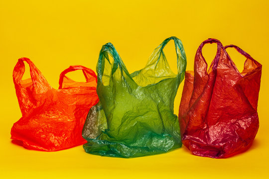 Three empty bright plastic bags on the bright yellow background