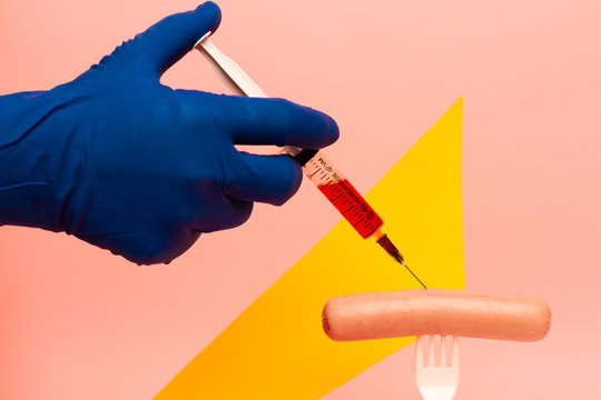 Injection of chemicals in sausage on fork. Food industry tools. 