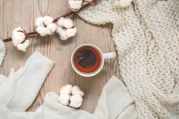 Background with warm sweaters and cup tea. Cozy still life in warm shades, space for text, Autumn winter concept. Copy Space.