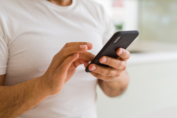 Close up of middle age man hands using smartphone at home