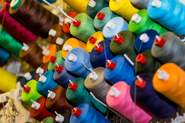 sewing threads in many different colors on a performed metal wall. Sewing workshop. Sewing tools. Tailor shop theme background, Textiles and clothing industry concept. selective focus.