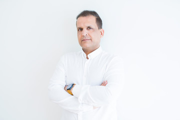 Middle age business man looking natural and relaxed with crossed arms over white wall background