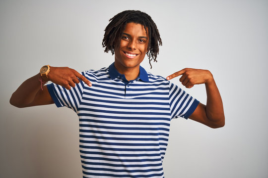Afro man with dreadlocks wearing striped blue polo standing over isolated white background looking confident with smile on face, pointing oneself with fingers proud and happy.