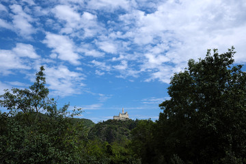 German castle Marksburg on the hill in the rhineland nad trees and blue sky with white clouds - Stockphoto