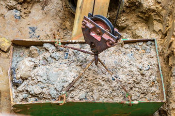 Digging a well, crane hook lifts the ground from the pit.