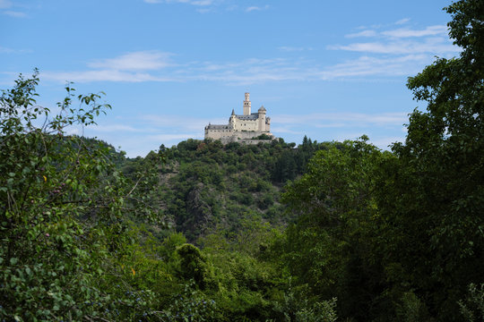 German castle Marksburg on the hill in the rhineland nad trees and blue sky with white clouds - Stockphoto