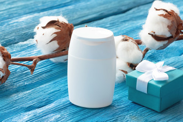 Cosmetic lotion white bottle or micellar water and a cotton branch on a blue wooden background.
