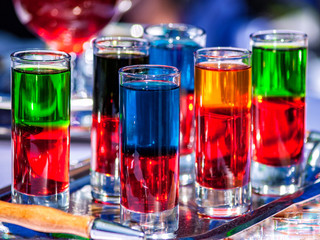 Drinks of different density and different colors are poured into glass containers