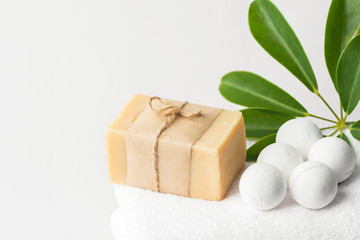 Obraz na płótnie Canvas Homemade vegan bath bombs artisan olive oil soap on white cotton terry towel green houseplant in bathroom. Spa wellness body care relaxation beauty concept. Poster with copy space