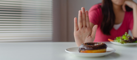 panoramic banner. Diet. young woman refuse delicious glazed donut, junk food or unhealthy food and...