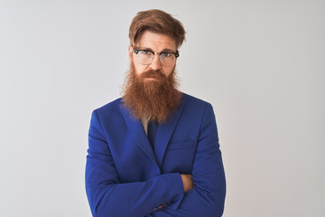 Young redhead irish businessman wearing suit and glasses over isolated white background skeptic and nervous, disapproving expression on face with crossed arms. Negative person.