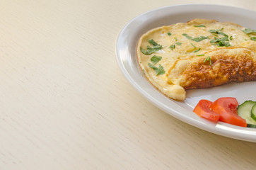 Omelet with cheese and parsley, sliced tomatoes and cucumbers on the plate. Scrambled eggs with copy space, close up view. Healthy nutrition.