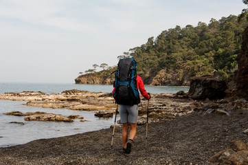 Fototapeta premium Girl walking on the beach with hiking backpack