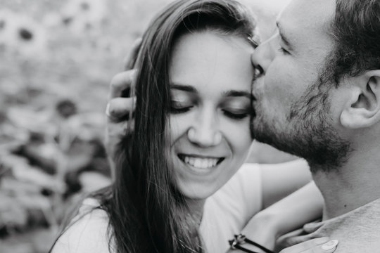 Black and white photo of a husband and wife couple in love. A man kisses a woman, a woman smiles with her eyes closed.