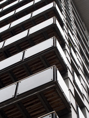 abstract corner view of a tall modern urban apartment building with black cladding and glass balconies