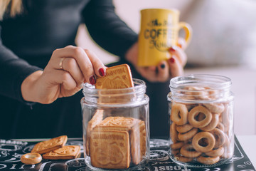 Close-up of cookies and a mug with tea on the table, cookies in female hands close-up