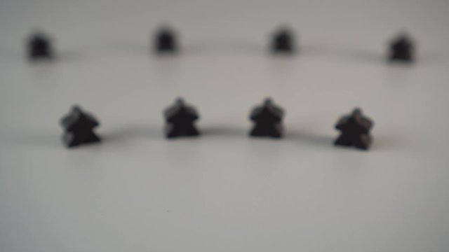 The hand removes the red figure from the environment of black figures on a gray surface. The concept of the dismissal of the leader from the team
