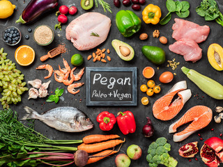 Pegan diet conept. Vegan plus paleo diet food ingredients - vegetables, fruits, raw meat and fish on dark background. Top view or flat lay