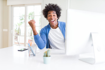 African American man working using computer screaming proud and celebrating victory and success very excited, cheering emotion