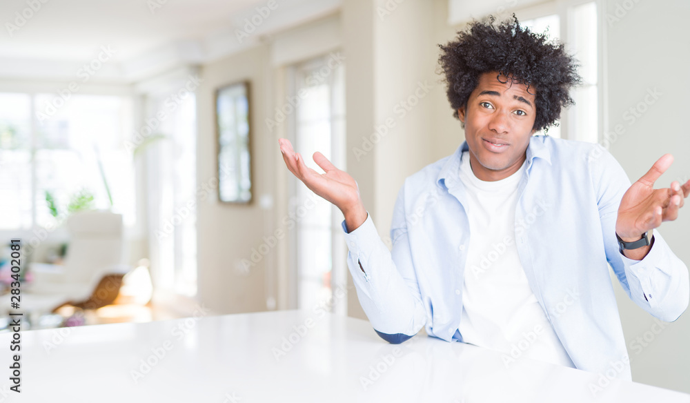 Canvas Prints African American man at home clueless and confused expression with arms and hands raised. Doubt concept.