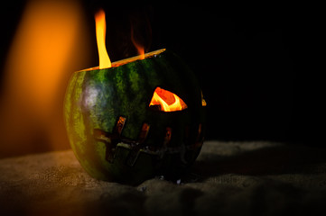 green watermelon burns with fiery flame on the scary holiday of october halloween