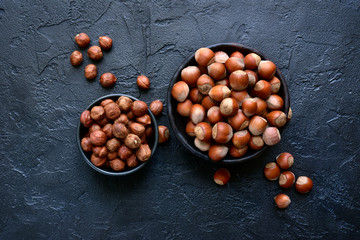 Peeled and unpeeled hazelnuts in a bowl.Top view with copy space.