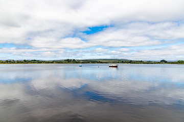 Boat in Lough Corrib with forest and farm fields in background