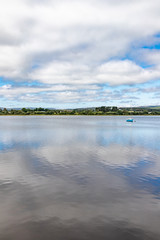 Boat in Lough Corrib with forest and farm fields in background