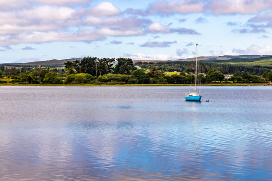 Boat in Lough Corrib with forest and farm fields in background