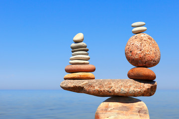 Stones balance on a background of blue sky and sea