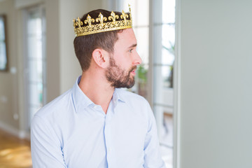 Handsome business man wearing golden crown as a king or prince looking to side, relax profile pose...