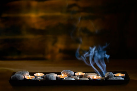 Candles with stones and smoke, from aroma cone on dark background 