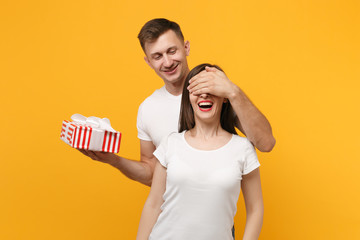 Pretty couple in white t-shirts posing isolated on yellow orange background. Valentine's Day,...