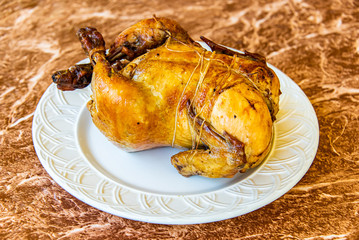 Whole Roasted Chicken on white plate and granite table top
