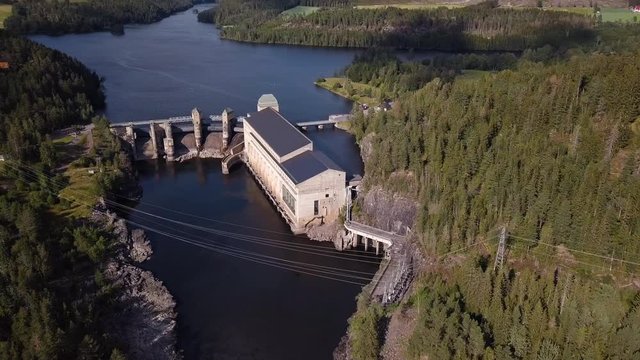 Aerial, tilt up, drone shot, panning towards the Solbersfossen hydro powerplant dam, at Glomma river, on a sunny day, in Spydeberg, Ostfold, Norway